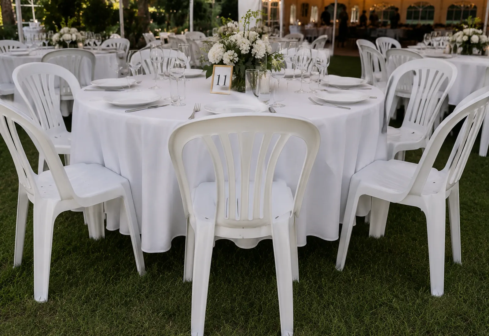 White plastic event chairs arranged around tables under a marquee